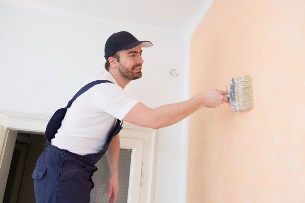 Man painting the house with peach