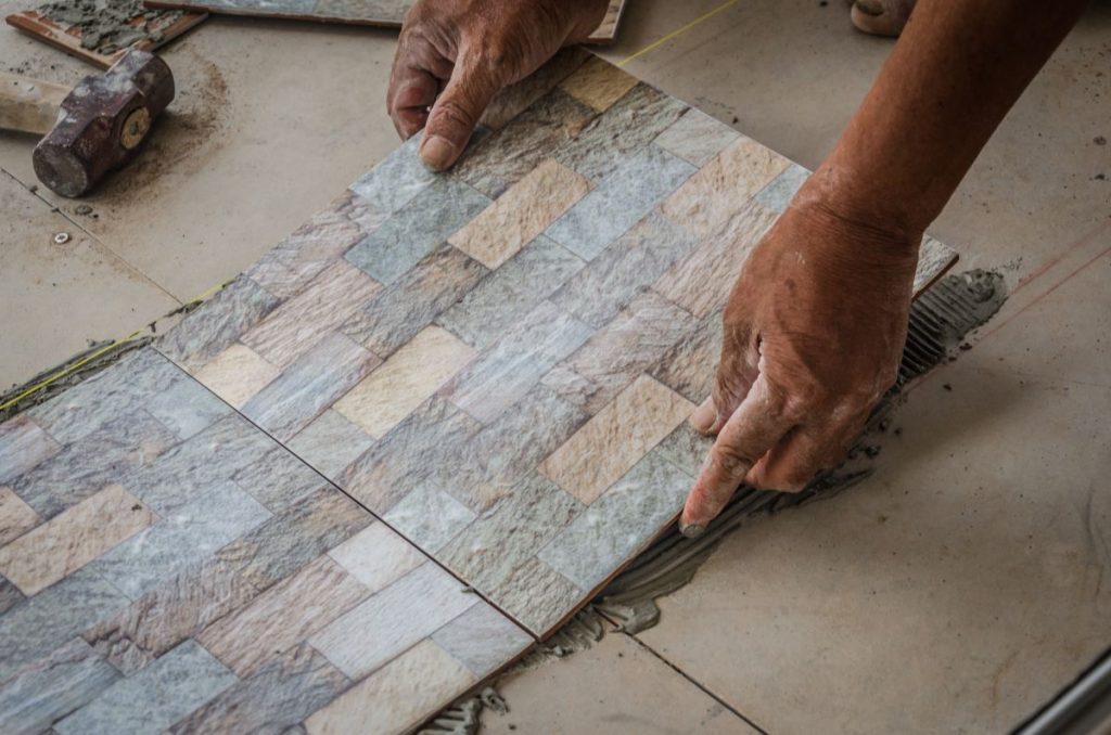man setting down flooring tiles