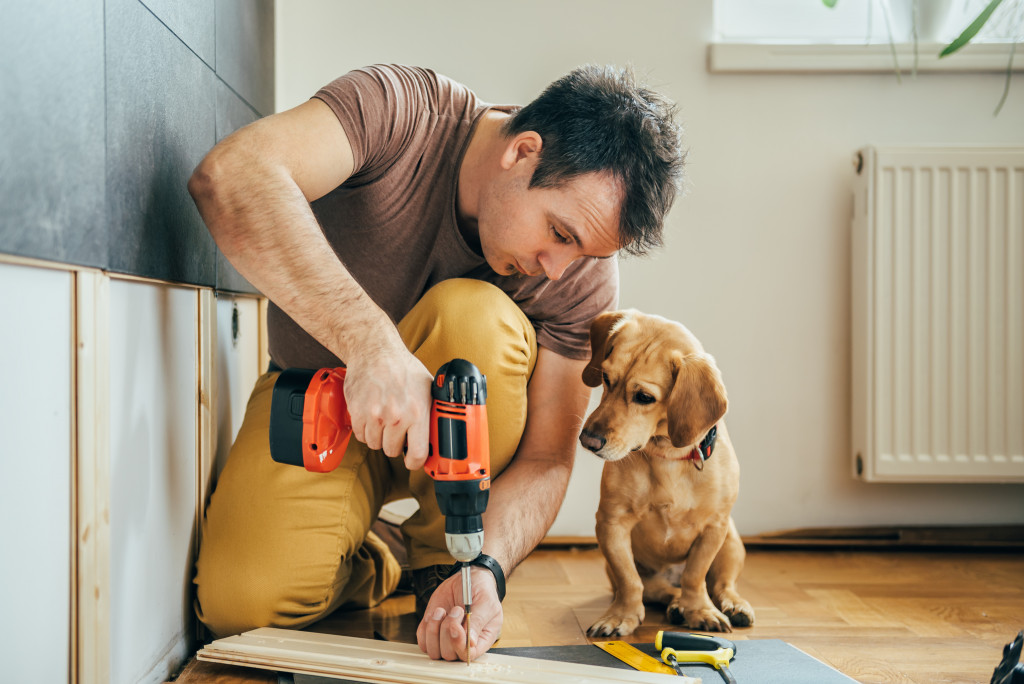 man doing DIY work with dog