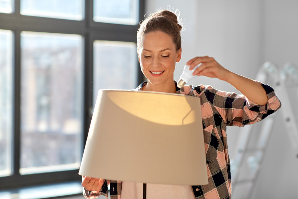 woman changing light bulb in floor lamp