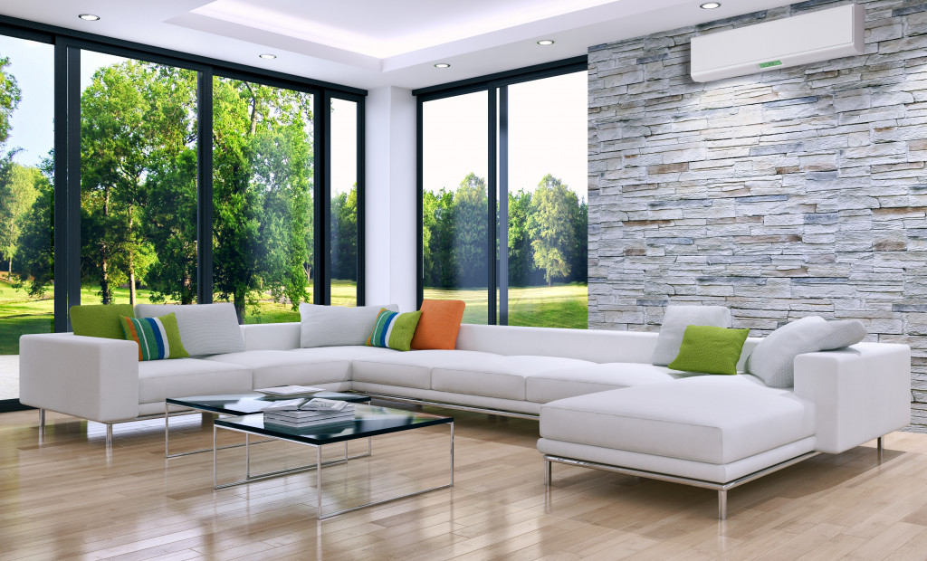 Bright living area with an air conditioner and floor to ceiling windows.