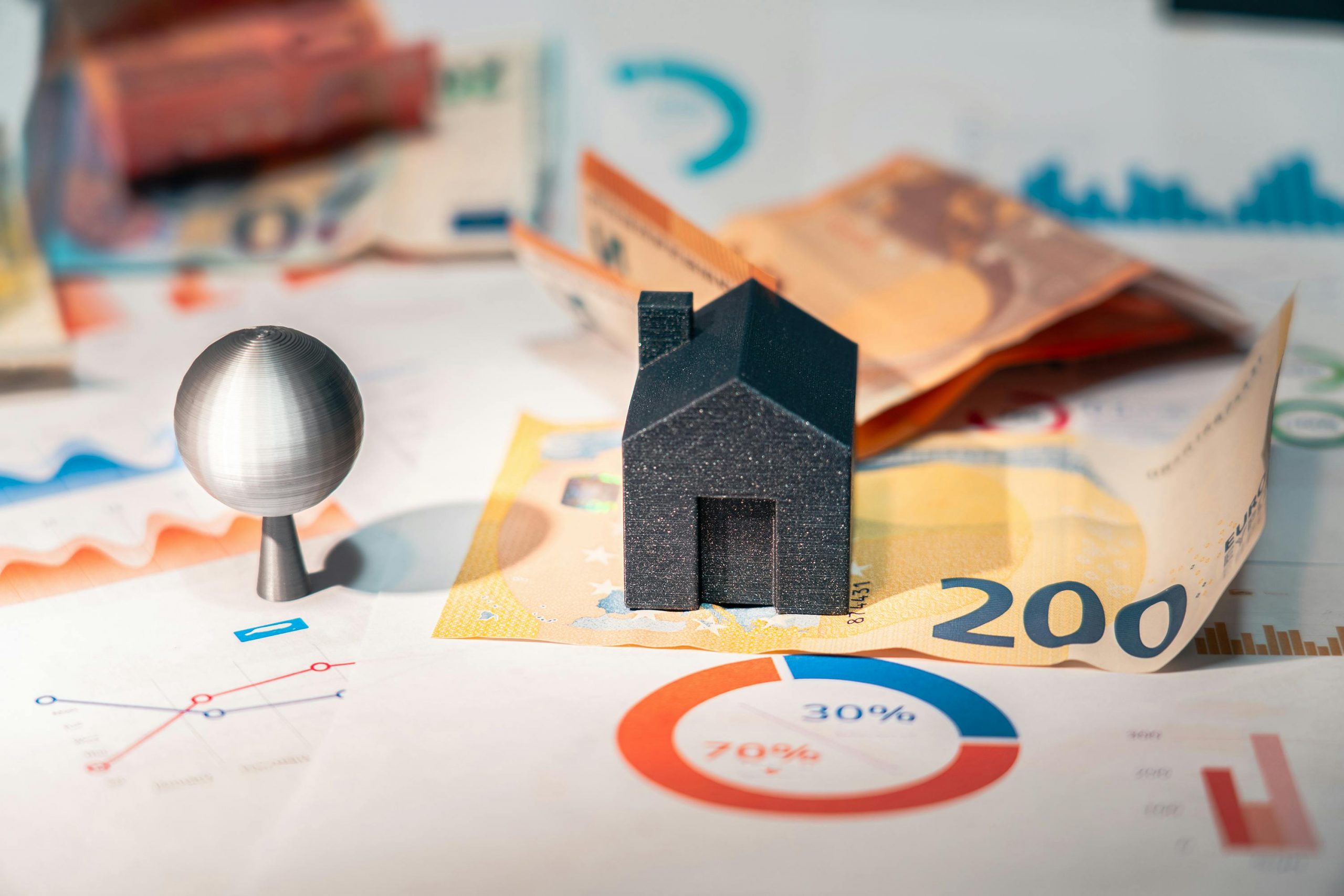 black model house placed on top of a banknote and financial charts